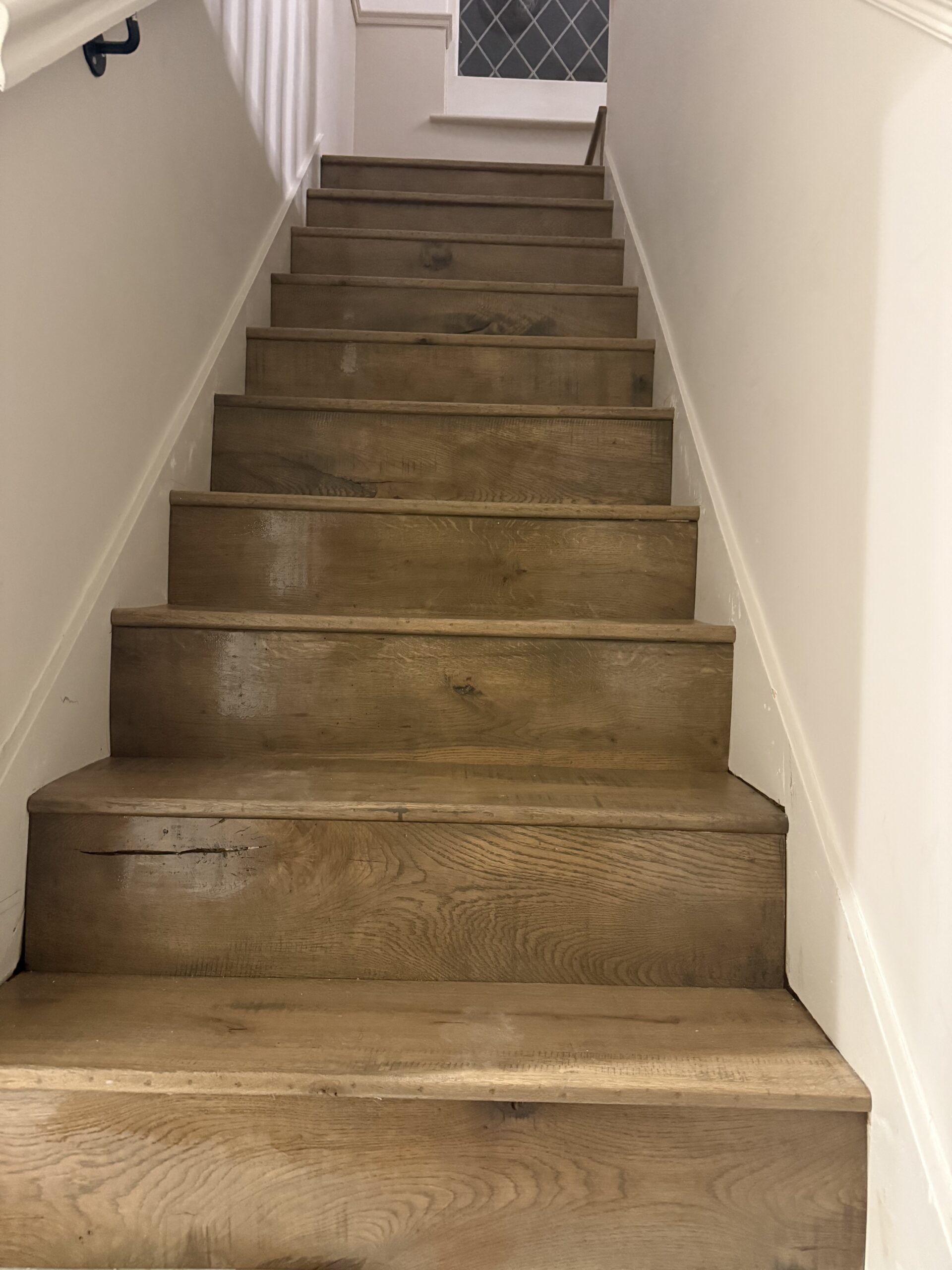 Wooden staircase with white walls and handrail