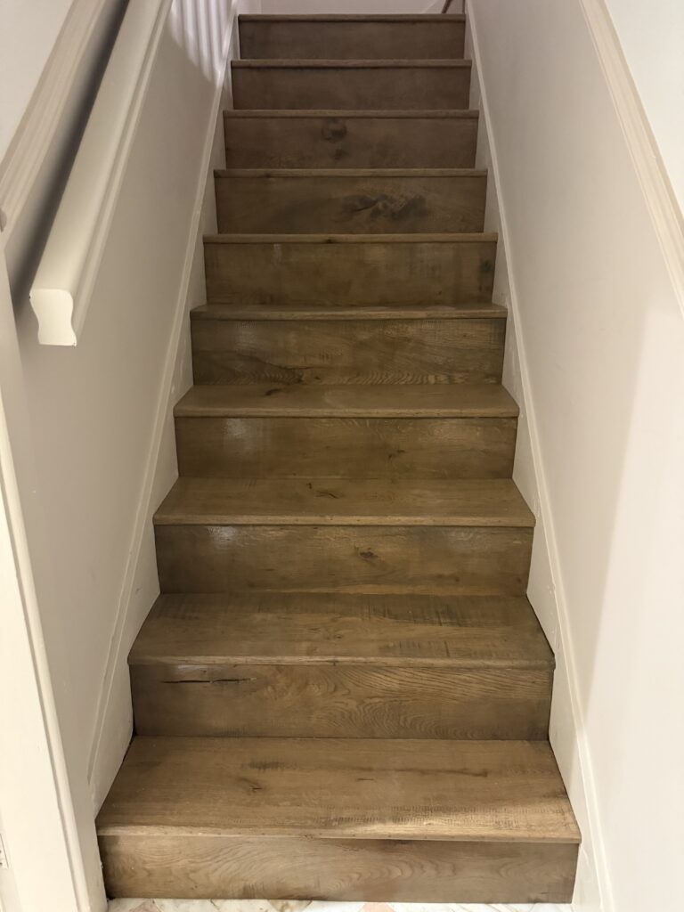 Wooden staircase with white walls and handrail