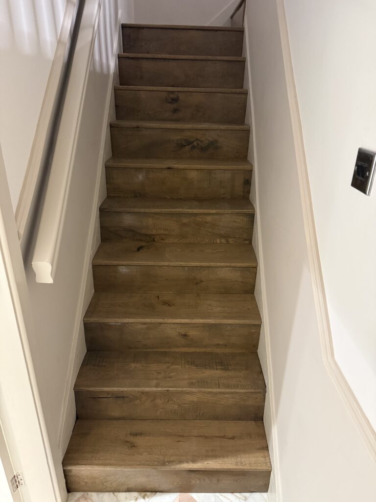 Wooden staircase with white walls and handrail