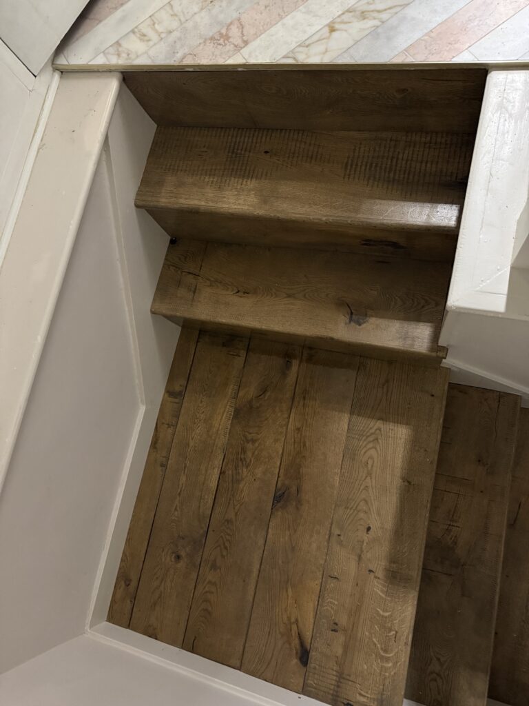 Wooden staircase with white walls viewed from above
