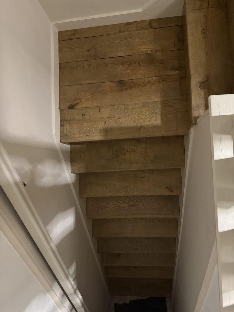 Wooden staircase with white walls and handrail
