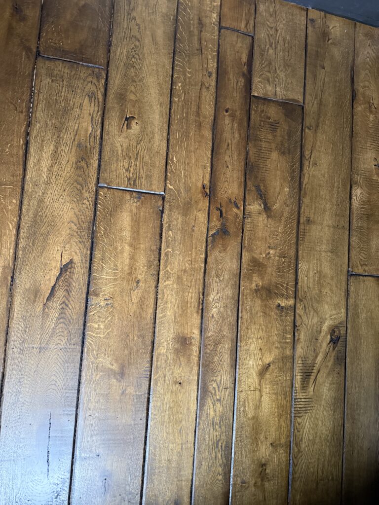 Brown wooden floor planks in staggered herringbone pattern